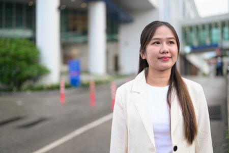 Portrait of Southeast Asian businesswoman outdoors in the city street during day wearing business attire and looking confidentの写真素材