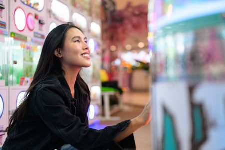 Happy young Asian woman playing arcade video games indoorsの写真素材