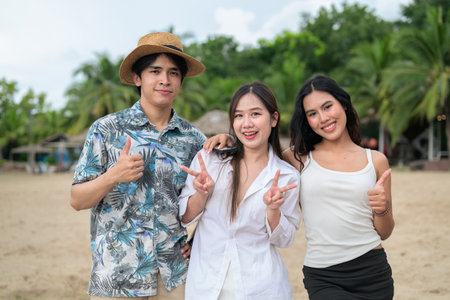 Three happy young Asian friends at beach smiling together during summer holiday vacationの写真素材