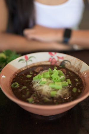 Famous Thailand street food boat noodles served at restaurant ready to be eaten by Asian woman