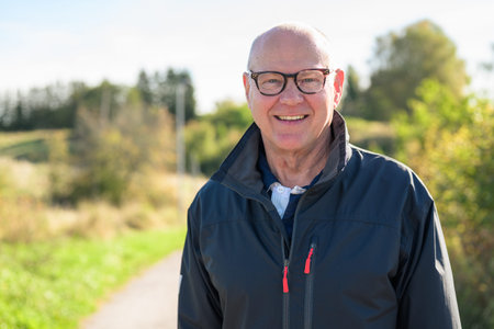 Portrait of a smiling senior man in casual clothing standing outdoors looking at cameraの写真素材