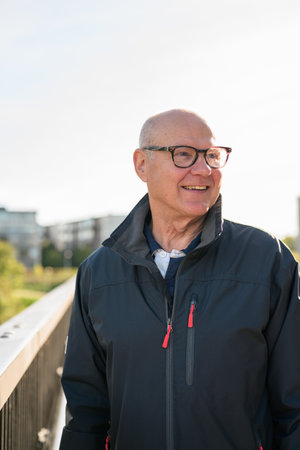 Portrait of a smiling Scandinavian senior man standing on a bridge in the cityの写真素材