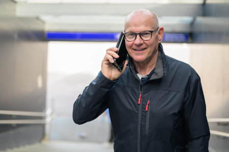 Portrait of senior man using mobile phone while standing in subway stationの写真素材