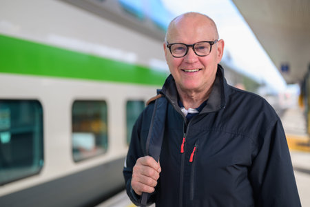 Portrait of smiling senior man with eyeglasses at train stationの写真素材