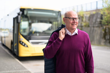 Portrait of a smiling senior Scandinavian male standing in front of a bus