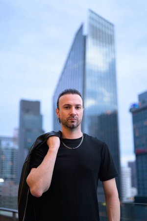 Handsome man wearing black leather jacket on rooftopの写真素材