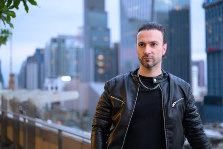 Handsome man wearing black leather jacket on rooftopの写真素材