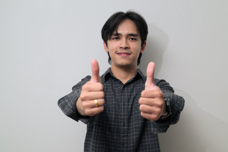 Portrait of handsome Young Asian Thai man in early 20s against white backgroundの写真素材