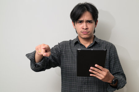 Portrait of young Asian Thai man in early 20s against white backgroundの写真素材