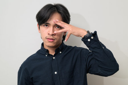 Portrait of handsome Young Asian Thai man in early 20s against white background