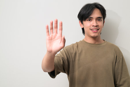 Portrait of handsome Young Asian Thai man in early 20s against white backgroundの写真素材