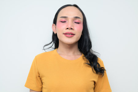 Studio portrait of a young Thai transgender individual with makeup and long hair. Concept of gender expression, LGBTQ pride, and inclusivity showing authentic beauty and diversity.の写真素材