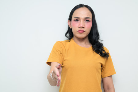 Studio portrait of a young Thai transgender individual with makeup and long hair. Concept of gender expression, LGBTQ pride, and inclusivity showing authentic beauty and diversity.の写真素材