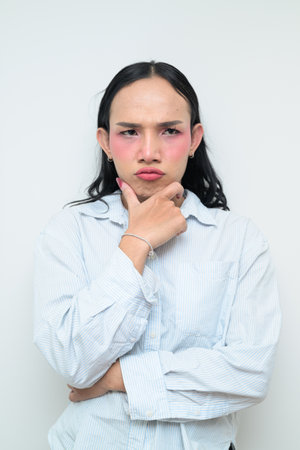 Studio portrait of a young Thai transgender individual with makeup and long hair. Concept of gender expression, LGBTQ pride, and inclusivity showing authentic beauty and diversity.の写真素材