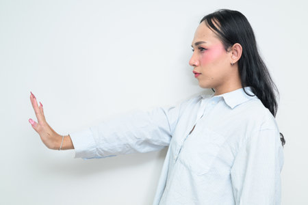 Studio portrait of a young Thai transgender individual with makeup and long hair. Concept of gender expression, LGBTQ pride, and inclusivity showing authentic beauty and diversity.の写真素材