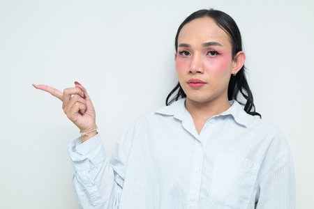 Studio portrait of a young Thai transgender individual with makeup and long hair. Concept of gender expression, LGBTQ pride, and inclusivity showing authentic beauty and diversity.の写真素材