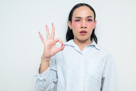 Studio portrait of a young Thai transgender individual with makeup and long hair. Concept of gender expression, pride, and inclusivity showing authentic beauty and diversity.の写真素材