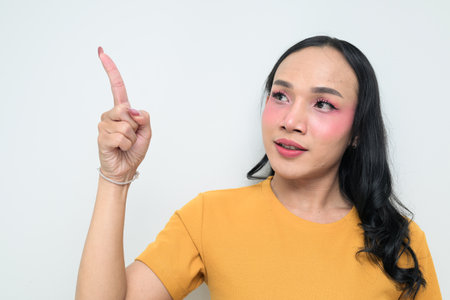 Studio portrait of a young Thai transgender individual with makeup and long hair. Concept of gender expression, LGBTQ pride, and inclusivity showing authentic beauty and diversity.の写真素材