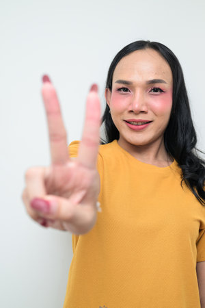 Studio portrait of a young Thai transgender individual with makeup and long hair. Concept of gender expression, LGBTQ pride, and inclusivity showing authentic beauty and diversity.の写真素材