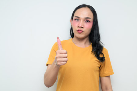 Studio portrait of a young Thai transgender individual with makeup and long hair. Concept of gender expression, LGBTQ pride, and inclusivity showing authentic beauty and diversity.の写真素材