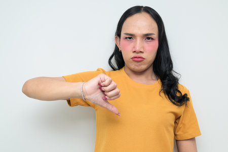 Studio portrait of a young Thai transgender individual with makeup and long hair. Concept of gender expression, LGBTQ pride, and inclusivity showing authentic beauty and diversity.の写真素材