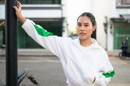 Happy young Asian woman in sporty activewear outdoors. Casual lifestyle portrait with cheerful expression, natural light, and positive energy for wellness, vitality, and fitness themes.の写真素材
