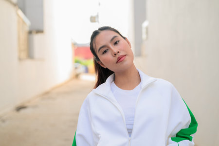 Happy young Asian woman in sporty activewear outdoors. Casual lifestyle portrait with cheerful expression, natural light, and positive energy for wellness, vitality, and fitness themes.の写真素材