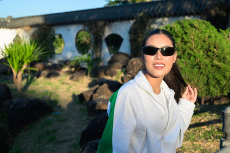 Happy young Asian woman in sporty activewear outdoors. Casual lifestyle portrait with cheerful expression, natural light, and positive energy for wellness, vitality, and fitness themes.の写真素材