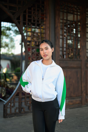 Happy young Asian woman in sporty activewear outdoors. Casual lifestyle portrait with cheerful expression, natural light, and positive energy for wellness, vitality, and fitness themes.の写真素材