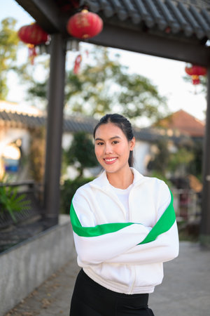 Happy young Asian woman in sporty activewear outdoors. Casual lifestyle portrait with cheerful expression, natural light, and positive energy for wellness, vitality, and fitness themes.の写真素材