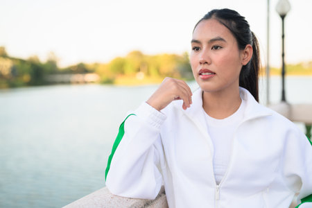 Happy young Asian woman in sporty activewear outdoors. Casual lifestyle portrait with cheerful expression, natural light, and positive energy for wellness, vitality, and fitness themes.の写真素材