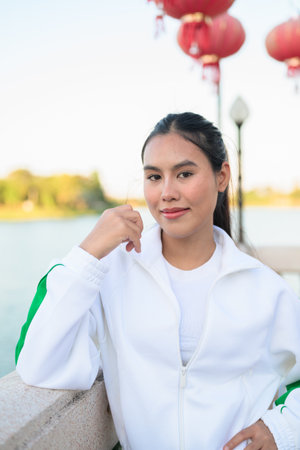 Happy young Asian woman in sporty activewear outdoors. Casual lifestyle portrait with cheerful expression, natural light, and positive energy for wellness, vitality, and fitness themes.の写真素材