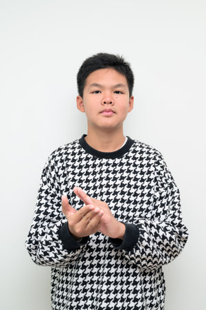 Studio portrait of an Asian teenage boy standing against a plain white background. Simple look suitable for youth, education, family, and lifestyle themes.の写真素材