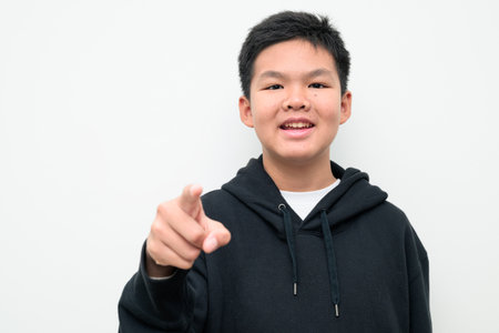 Studio portrait of an Asian teenage boy standing against a plain white background wearing black hoodie. Simple look suitable for youth, education, family, and lifestyle themes.の写真素材
