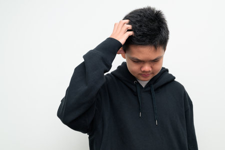 Studio portrait of an Asian teenage boy standing against a plain white background wearing black hoodie. Simple look suitable for youth, education, family, and lifestyle themes.の写真素材