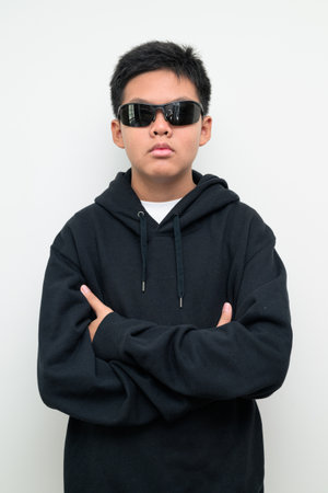 Studio portrait of an Asian teenage boy standing against a plain white background wearing black hoodie. Simple look suitable for youth, education, family, and lifestyle themes.の写真素材