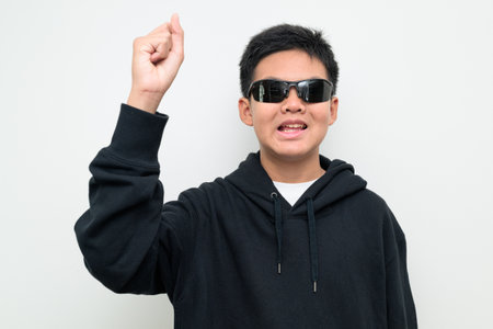 Studio portrait of an Asian teenage boy standing against a plain white background wearing black hoodie. Simple look suitable for youth, education, family, and lifestyle themes.の写真素材