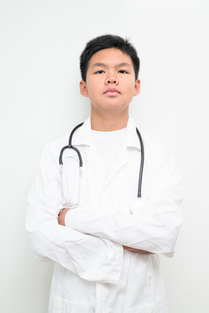 Portrait of a young Asian boy wearing a white lab coat and stethoscope. Suitable for healthcare, medical education, children profession dreams, and future doctor concepts.の写真素材