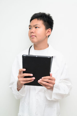 Portrait of a young Asian boy wearing a white lab coat and stethoscope. Suitable for healthcare,...