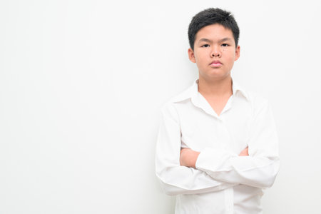 Studio portrait of an Asian teenage boy student standing against a plain white background wearing button down shirt. Simple look suitable for youth, education, family, and lifestyle themes.の写真素材