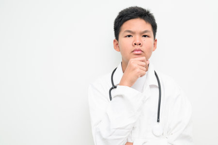 Portrait of a young Asian boy wearing a white lab coat and stethoscope. Suitable for healthcare, medical education, children profession dreams, and future doctor concepts.の写真素材