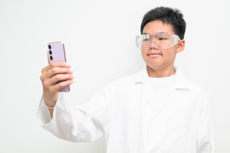 Portrait of a young Asian boy wearing a white lab coat and protective glasses. Suitable for healthcare, medical education, children profession dreams, and future scientist researcher concepts.の写真素材