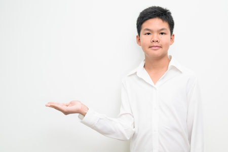 Studio portrait of an Asian teenage boy student standing against a plain white background wearing button down shirt. Simple look suitable for youth, education, family, and lifestyle themes.の写真素材