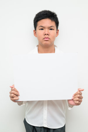 Studio portrait of an Asian teenage boy student standing against a plain white background wearing button down shirt. Simple look suitable for youth, education, family, and lifestyle themes.の写真素材