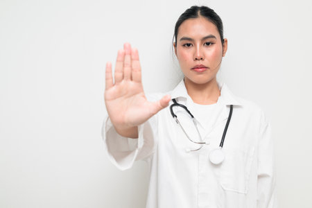 Portrait of a female healthcare professional in a white medical uniform with a stethoscope, standing against a clean studio background.の写真素材