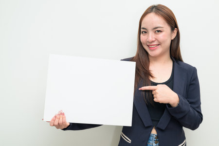 Studio portrait of a young Asian businesswoman against white background showing copy spaceの写真素材