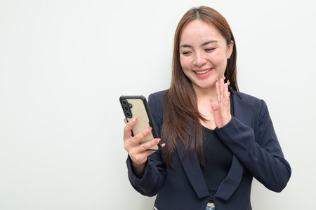 Studio portrait of a young Asian businesswoman against white background using mobile phoneの写真素材