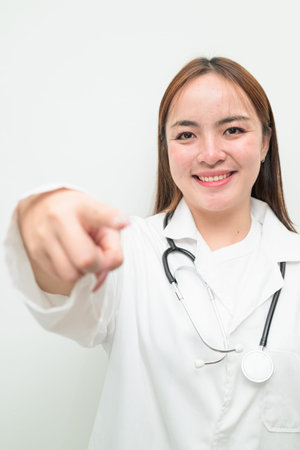 Portrait of young Asian female doctor against white background wearing lab coat and stethoscopeの写真素材