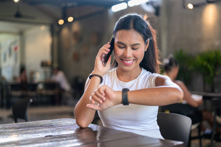 Smiling woman sitting indoors using mobile phone in coffee shopの写真素材