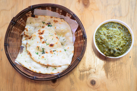 Top View of Indian Palak Paneer Curry With Garlic Naan Bread on Wooden Table